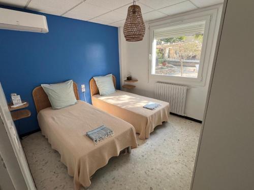a blue room with two beds and a window at Meublé tourisme 4*, les pieds dans l'eau, Villa LAS PALMERAS in La Londe-les-Maures