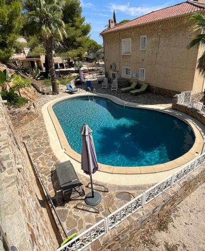 - une piscine avec un parasol et une chaise dans l'établissement Meublé tourisme 4*, les pieds dans l'eau, Villa LAS PALMERAS, à La Londe-les-Maures