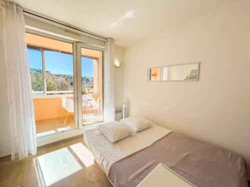 une chambre avec un lit et une grande fenêtre dans l'établissement Coquet studio dans résidence avec piscine Sanary, à Les Playes