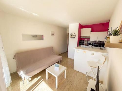 un petit salon avec un canapé et une cuisine dans l'établissement Coquet studio dans résidence avec piscine Sanary, à Les Playes