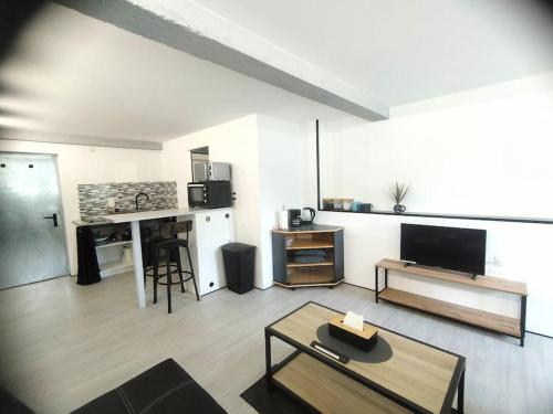 a living room with a table and a kitchen and a living room at Charmant studio pour 3 personnes in Briec