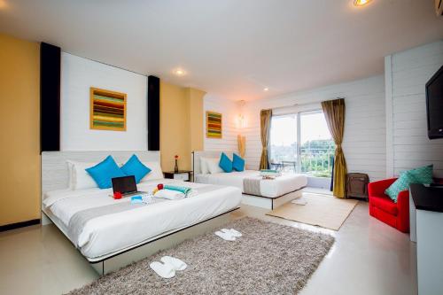 a bedroom with two beds and a couch and a tv at Anchor Boutique House in Patong Beach