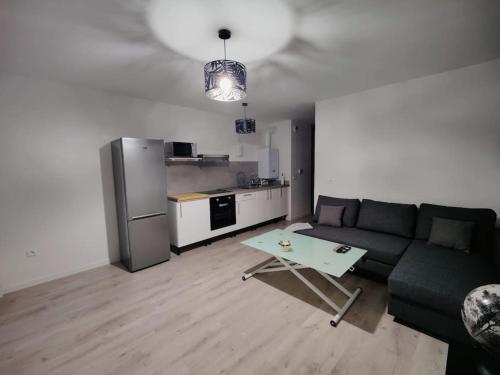un salon avec un canapé noir et une cuisine dans l'établissement Logement calme et agréable Privé et non partagé, à Groslay