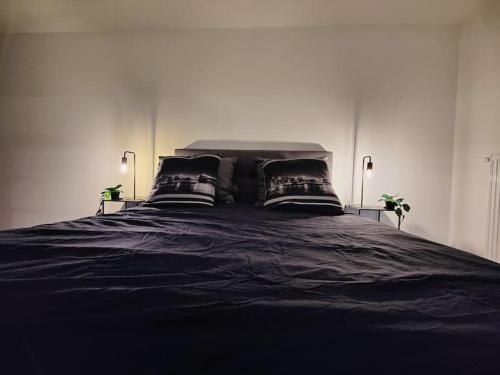 - un grand lit noir avec 2 oreillers dans l'établissement Logement calme et agréable Privé et non partagé, à Groslay