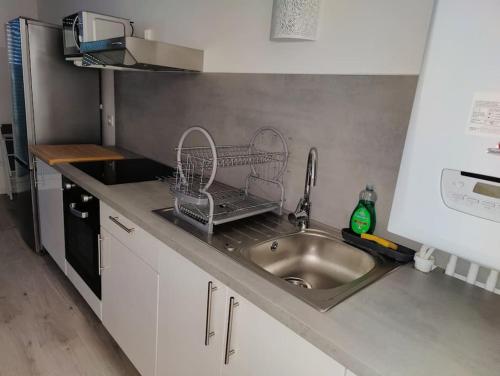 un comptoir de cuisine avec évier et étendoir à vaisselle dans l'établissement Logement calme et agréable Privé et non partagé, à Groslay