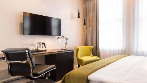 a hotel room with a bed and a desk and a tv at Holiday Inn Dresden - Am Zwinger by IHG in Dresden