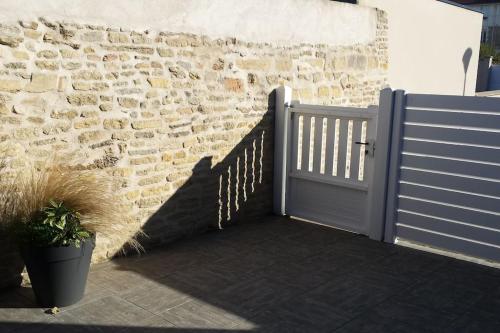 a gate to a brick wall with a door at Bois joli - Maison classée 3 étoiles, à 2 pas de la plage in Langrune-sur-Mer