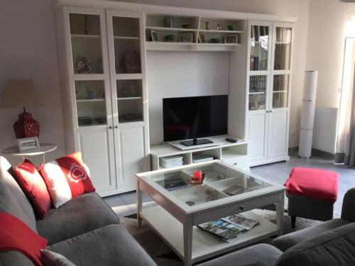 a living room with a couch and a tv at Bois joli - Maison classée 3 étoiles, à 2 pas de la plage in Langrune-sur-Mer