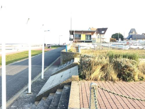 a road with a fence and a street with a house at Bois joli - Maison classée 3 étoiles, à 2 pas de la plage in Langrune-sur-Mer