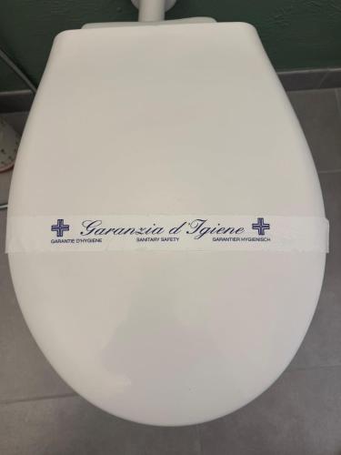 a white toilet seat with a sign on it at La Cascina di Bea in Torre Boldone