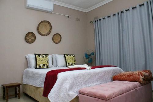 ein Schlafzimmer mit einem Bett und einer rosa Couch in der Unterkunft Lulu Guest Lodge, Low-Density Suburbs, Victoria Falls in Victoriafälle