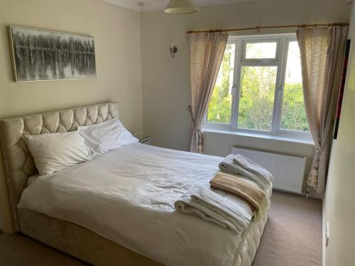 a bedroom with a bed with white sheets and a window at Delux 5 bed house lots private car parking, short walk to high st, shops in Fleet