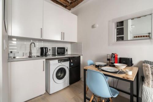 une cuisine avec une table et une machine à laver dans l'établissement Studio en plein Coeur du Marais, à Paris