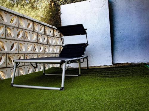 a chair sitting on the grass next to a wall at Manomar II, tu refugio en Gata in Gata