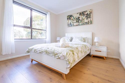 a white bedroom with a bed and a window at Hidden Gem - 3 bedroom townhouse in Heidelberg West in Melbourne