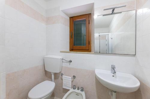 a white bathroom with a toilet and a sink at Camping Bungalow Lido in Capoliveri