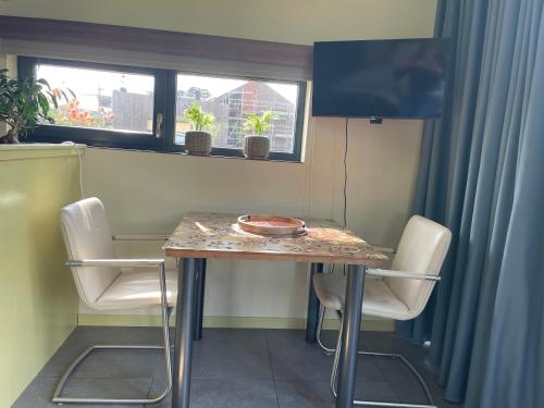 a table with chairs and a television in a room at Casitas Wijchen - Nijmegen in Wijchen