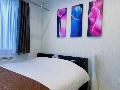 a bedroom with a bed and three paintings on the wall at yuga hotel tokiwadai in Tokyo