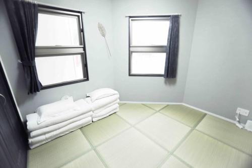 a white room with two windows and a tiled floor at yuga hotel tokiwadai in Tokyo