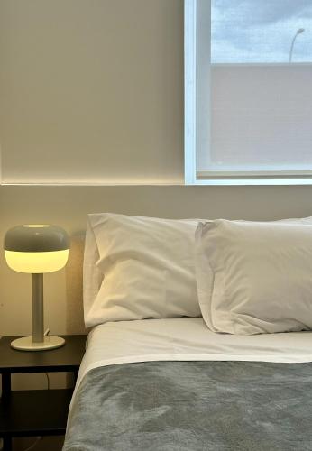 a bed with white sheets and a lamp on a table at Apartamentos Noviembre in Madrid