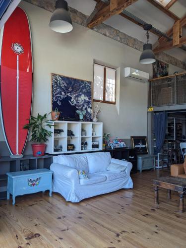 - un salon avec un canapé et une planche de surf sur le mur dans l'établissement Magnifique loft sur la plage Life is a Beach GuestHouse, à Théoule-sur-Mer