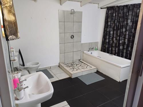 um banheiro com uma pia, uma banheira e um vaso sanitário em Platinum Guesthouse em Klerksdorp