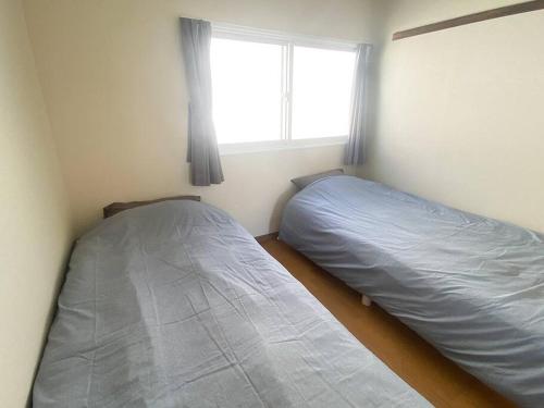 two beds in a small room with a window at Tasogare Apartment 201 in Hakodate