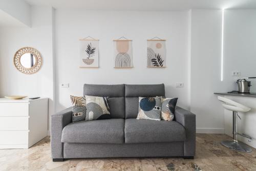 a gray couch in a living room with a mirror at Canteras 1º Linea de Playa in Las Palmas de Gran Canaria