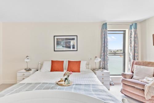 a white bedroom with a bed and a chair at B6 Masts - With sea views, parking and terrace in Torquay