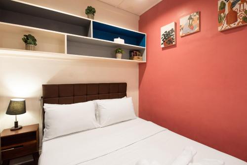 a bedroom with a white bed and a red wall at Homey and Cozey Poblacion Makati S02 in Manila