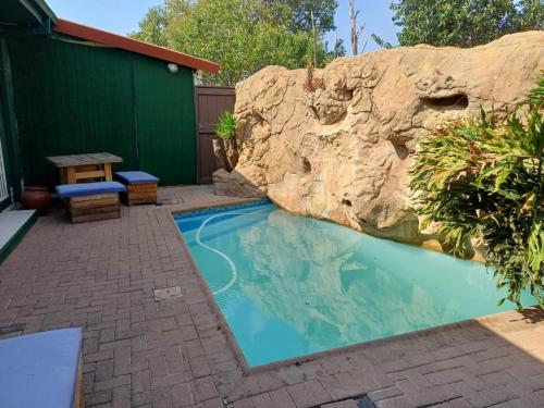 uma piscina com uma parede de pedra ao lado em Platinum Guesthouse em Klerksdorp
