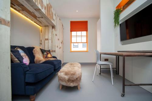 a living room with a blue couch and a table at Higgihaus Aparthotel, Clare Street in Bristol