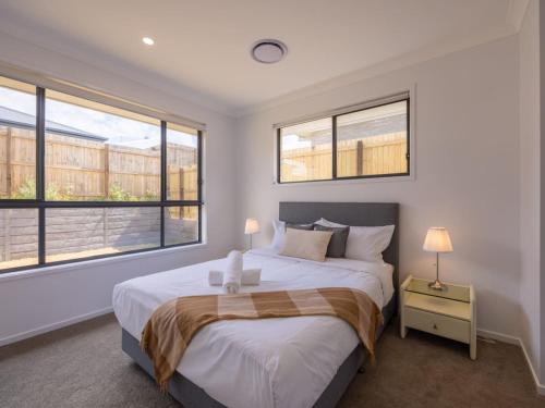 ein Schlafzimmer mit einem großen Bett mit zwei Fenstern in der Unterkunft Brand New 4Bs Home near Shops and Park at Greenbank in Greenbank