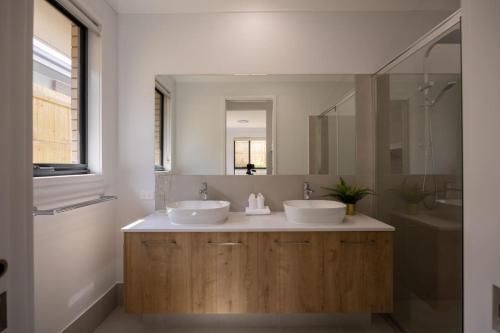 ein Badezimmer mit zwei Waschbecken und einem großen Spiegel in der Unterkunft Brand New 4Bs Home near Shops and Park at Greenbank in Greenbank