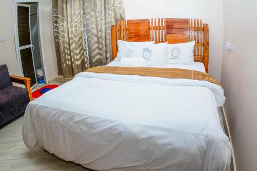 a bedroom with a large white bed with a wooden headboard at BEZINDA LODGE in Dodoma