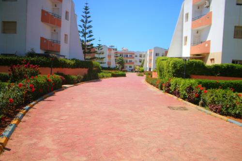 a red brick walkway between two buildings with flowers at Mohammedia 2 in Mohammedia