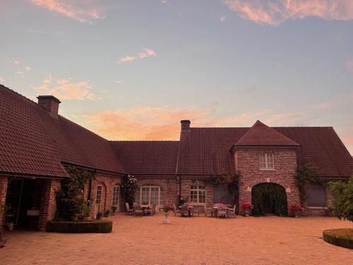 a brick building with tables and chairs in a courtyard at Imagine B&B in Wortegem