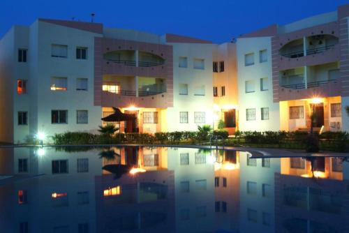 an apartment building at night with its reflection in the water at Mohammedia 2 in Mohammedia