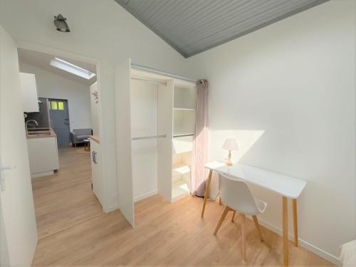 Cette chambre comprend un bureau blanc et une table. dans l'établissement T3 plein centre proche Versailles Saint Quentin en Yvelines, à Voisins-le-Bretonneux
