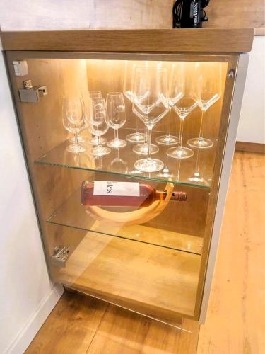 a wine bottle and glasses in a glass case at Three Diamonds Residence in Dunajská Streda