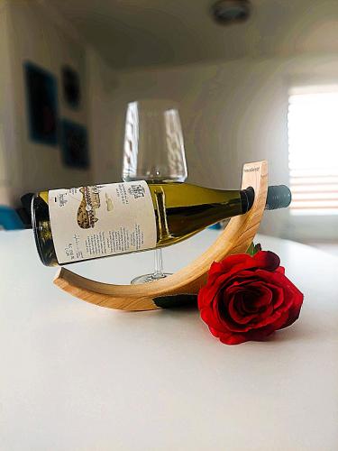 a bottle of wine and a glass and a rose at Three Diamonds Residence in Dunajská Streda