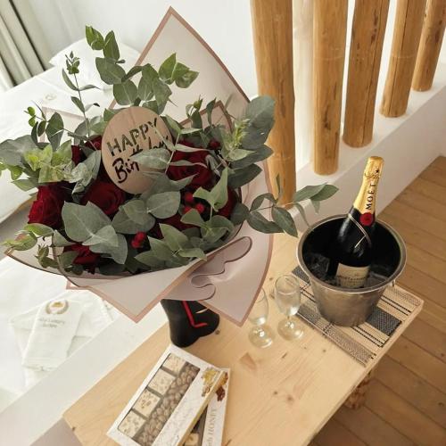 a bouquet of flowers on a table with a bottle of wine at Alia Suites and Spa in Haraki