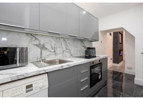 a white kitchen with a sink and a microwave at Spacious Manchester Duplex 2BR Parking Sleeps 6 in Bolton