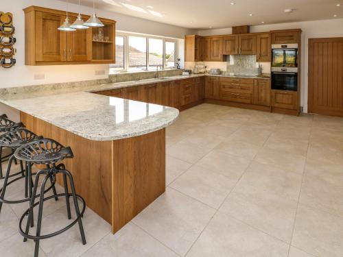 a large kitchen with wooden cabinets and a large island at Little Pale in Whitland