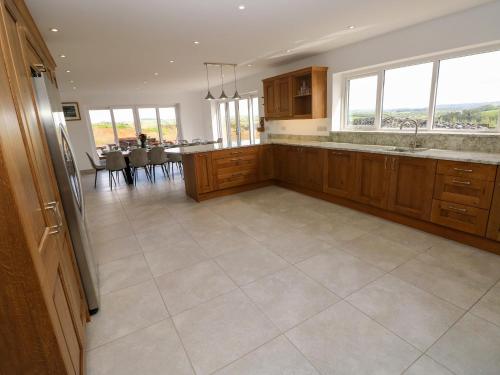 a large kitchen with wooden cabinets and a large tile floor at Little Pale in Whitland