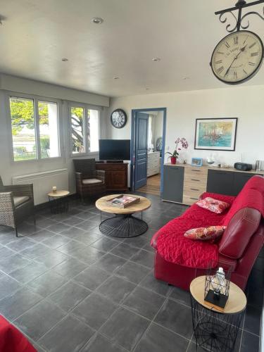 - un salon avec un canapé rouge et une horloge murale dans l'établissement villa les pieds dans l eau, à Carnac