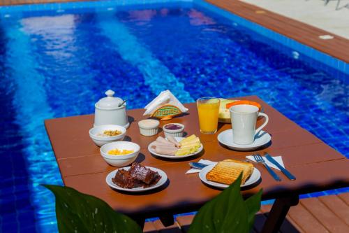 een tafel met ontbijtproducten en drankjes naast een zwembad bij Pousada Brisas de Búzios in Búzios