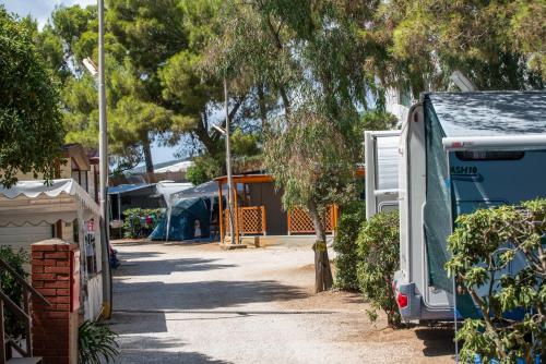 an rv parked in a yard with tents at Camping Bungalow Lido in Capoliveri