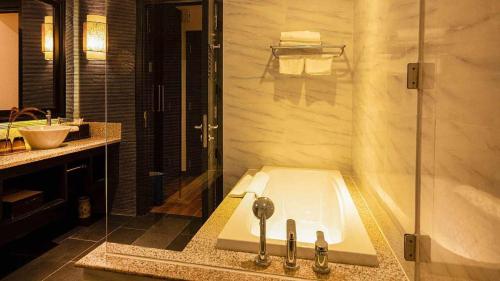 a bathroom with a tub and a shower and a sink at ROBINSON Nam Hoi An in Tam Ky