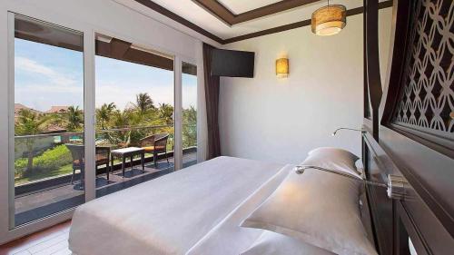 a bedroom with a bed and a balcony with a view at ROBINSON Nam Hoi An in Tam Ky